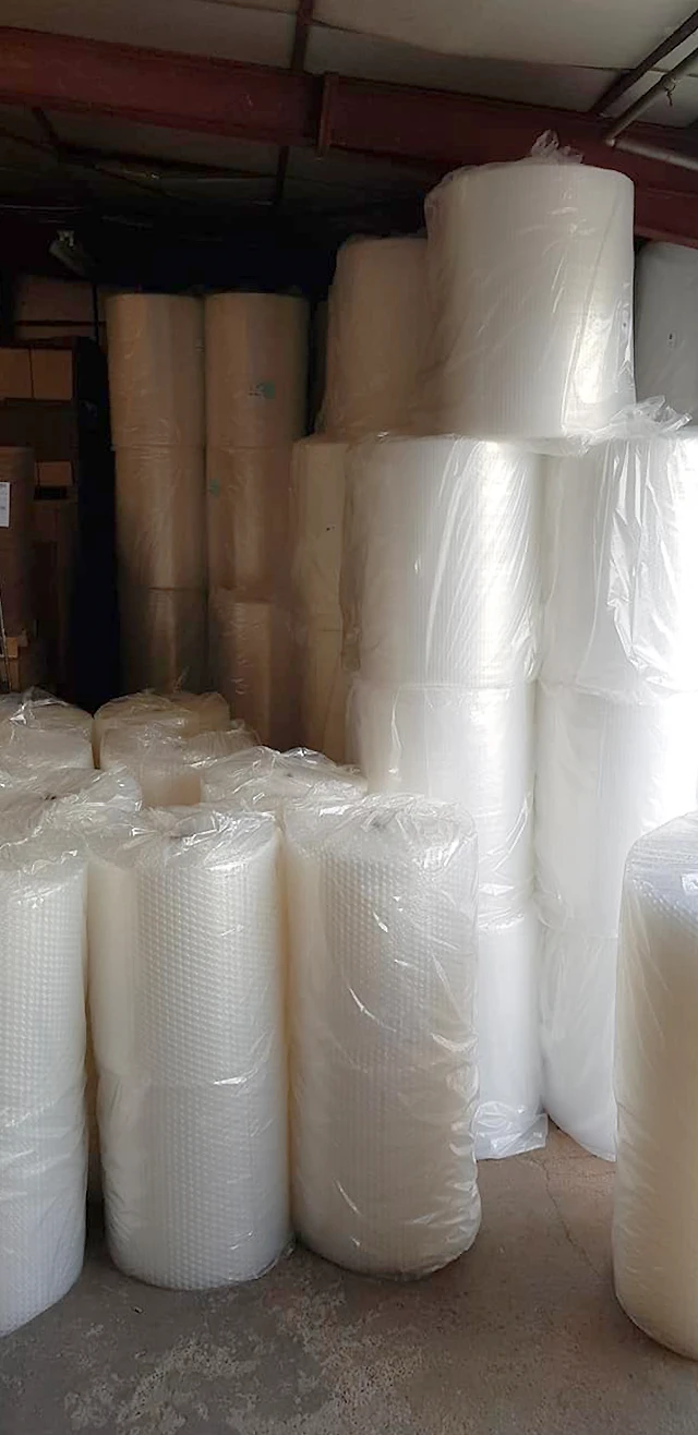 Entrepôt industriel stockant de grandes quantités de rouleaux d'emballage protecteur empilés jusqu'au plafond