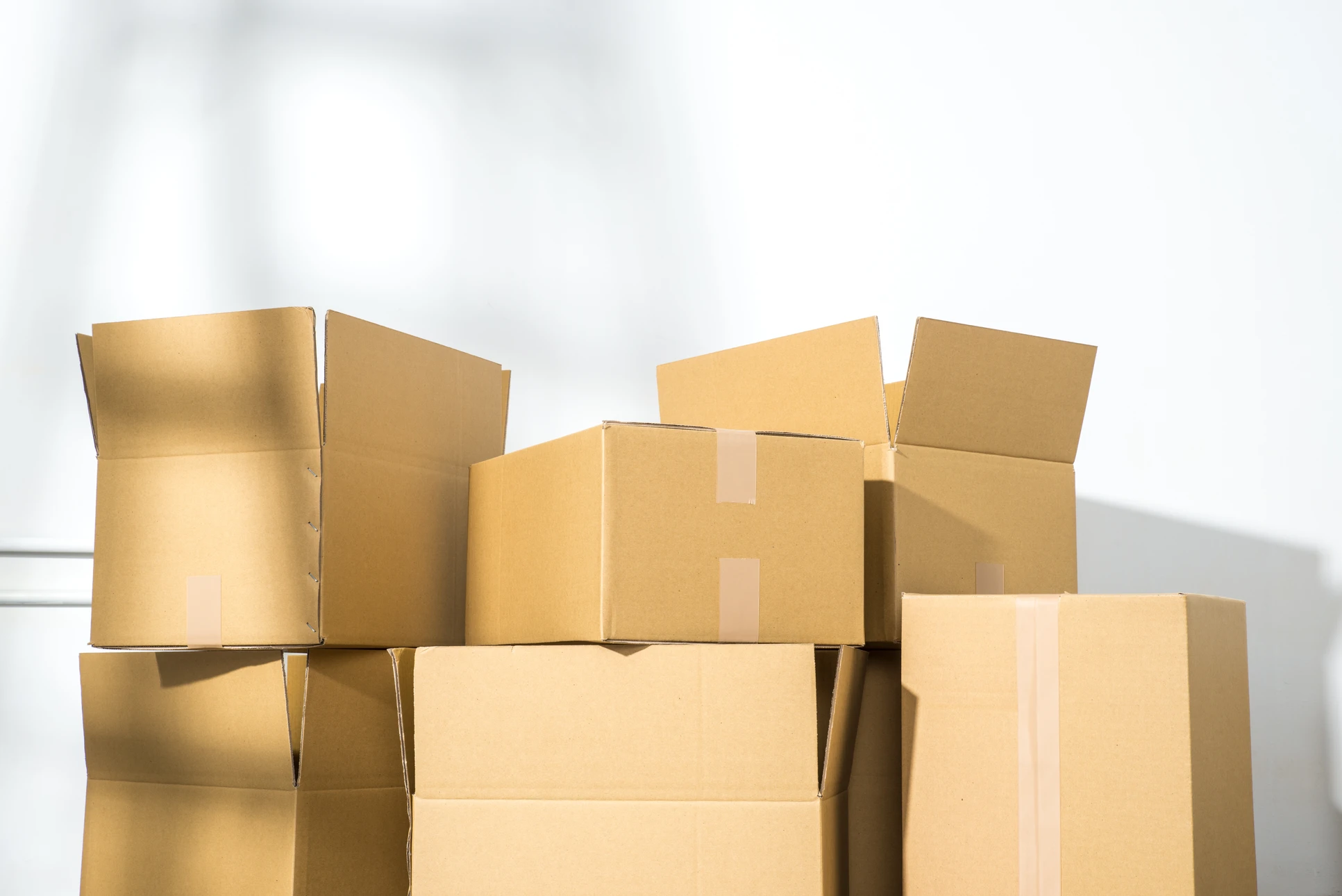 Entrepôt industriel avec employé en tenue de travail manipulant des colis en carton ondulé